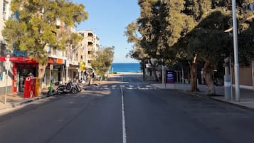Une rue côtière bordée d’immeubles et d’arbres, offrant une vue dégagée sur la mer.