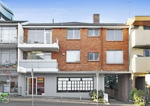 Een woonhuis met twee verdiepingen, een bakstenen gevel, een balkon op de bovenverdieping en een garage-ingang.