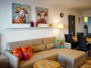 Una sala de estar con un sofá, dos almohadas, una mesita redonda y un comedor con sillas y una mesa.