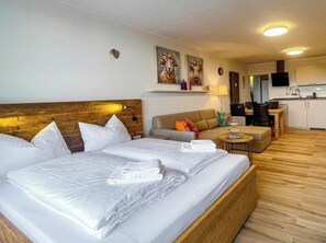 A hotel room with a large bed, a sofa, a small table, and a kitchenette in the background. - Holiday Apartment 610 (Winterberg)