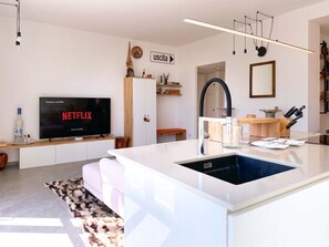 A modern kitchen with a central island, a built-in sink, and a flat-screen TV mounted on the wall. - Casa Cenni | Bright 2BR, M1 & CityLife (Milano)
