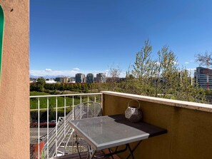 Ein Balkon mit einem Metalltisch und Stuhl, einer dekorativen Laterne und Blick auf Gebäude und Bäume.