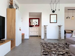 Ein modernes Wohnzimmer mit einem Flachbildfernseher, Holzmöbeln, einem gemusterten Teppich und einem spiegeln mit rotem Rahmen.