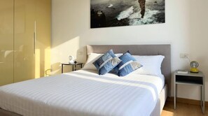 A bedroom with a bed, a nightstand, a lamp, and a painting on the wall. - Casa Cenni | Bright 2BR, M1 & CityLife (Milano)