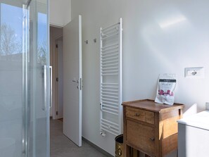 Ein Badezimmer mit einer weißen Heizung, einem Holzschrank und einem Begrüßungskit an der Wand.
