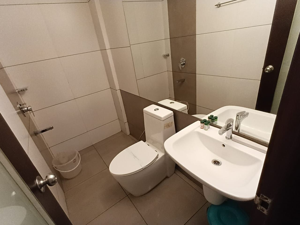 A small bathroom with a toilet, a sink, and a mirror.