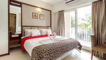 Habitación de hotel con una cama grande, un espejo, un ventanal con cortinas y un equipo de aire acondicionado.