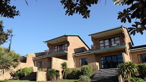 Un edificio de dos pisos con techo plano, un balcón en el segundo nivel y una escalera que conduce a la entrada.