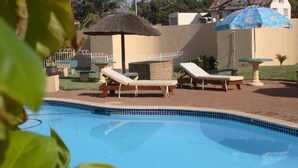 Una piscina con sillas de descanso y una zona sombreada.