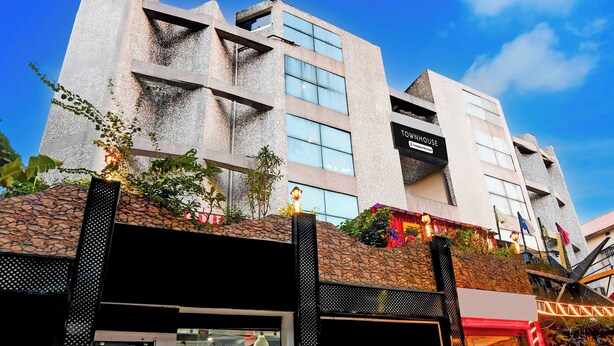 Un bâtiment moderne avec une façade en pierre, de nombreuses fenêtres et une enseigne indiquant qu’il s’agit d’une maison de ville gérée par une entreprise de services.