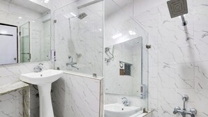 Une salle de bain moderne avec un lavabo en marbre blanc, une douche en verre et un grand miroir.
