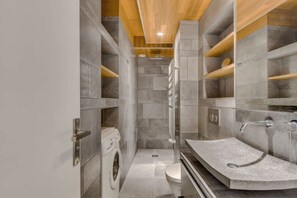 Ein modernes Badezimmer mit Waschmaschine, Dusche und Waschbecken mit Granitplatte.