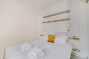 Ein modernes Hotelzimmer mit einem ordentlich bezogenen Bett, einem Nachttisch und einer wandmontierten Lampe.