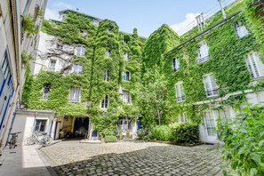 Ein Innenhof mit Kopfsteinpflasterböden, umgeben von mit Grünbecken bewachsenen Gebäuden.