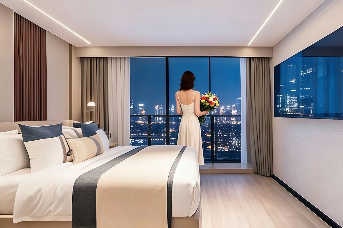 Una camera d'albergo moderna con un letto grande, vista sulla città e una persona che tiene un bouquet di fiori.