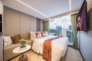 Una moderna camera d'hotel con vista sulla città, un letto, un divano e un tavolino con un vaso.