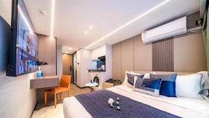 A modern hotel room with a bed, a desk, a chair, a TV, and an air conditioning unit. - Yunli Cloudtop Hotel (Guangzhou)
