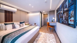 A modern hotel room with a bed, a desk, and a chair. There is a poster on the wall and an air conditioning unit above the bed. - Yunli Cloudtop Hotel (Guangzhou)