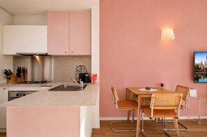A modern kitchen with a central island, a dining area with a table and chairs, and a cityscape painting on the wall. - Empire Theatre Loft Your Colourful Melbourne Stay (Melbourne)