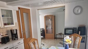 Una cocina compacta con comedor, que incluye un microondas, cafetera y un reloj en la pared.