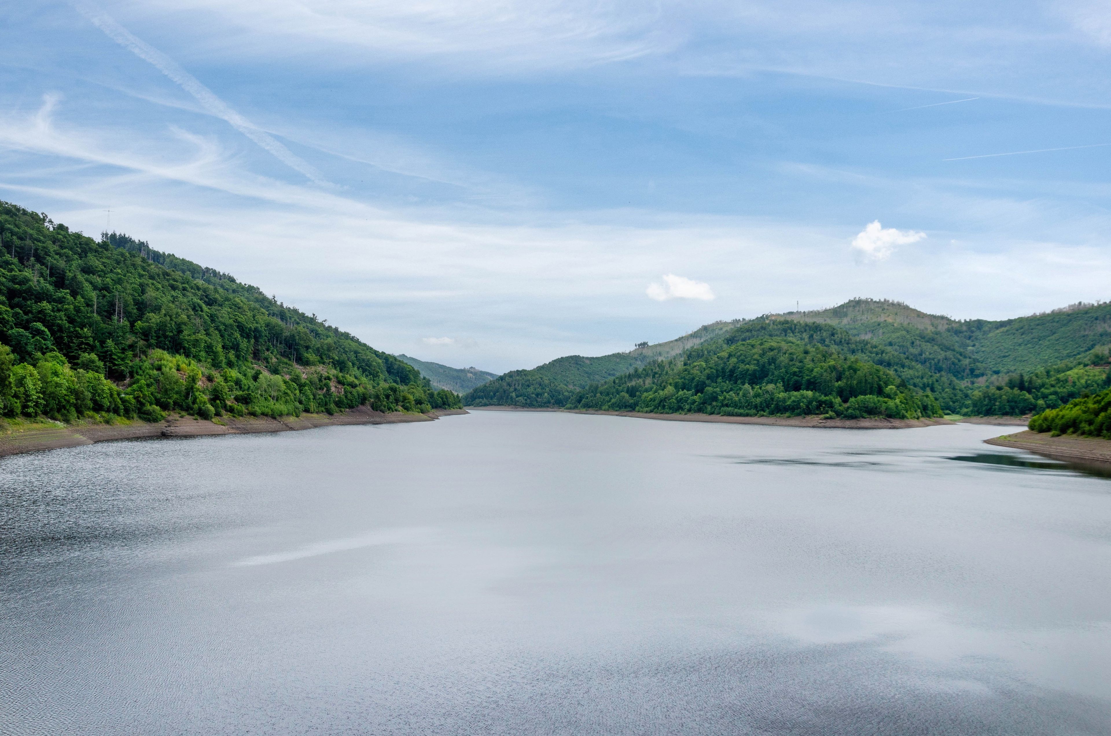 A calm lake surrounded by forested hills.