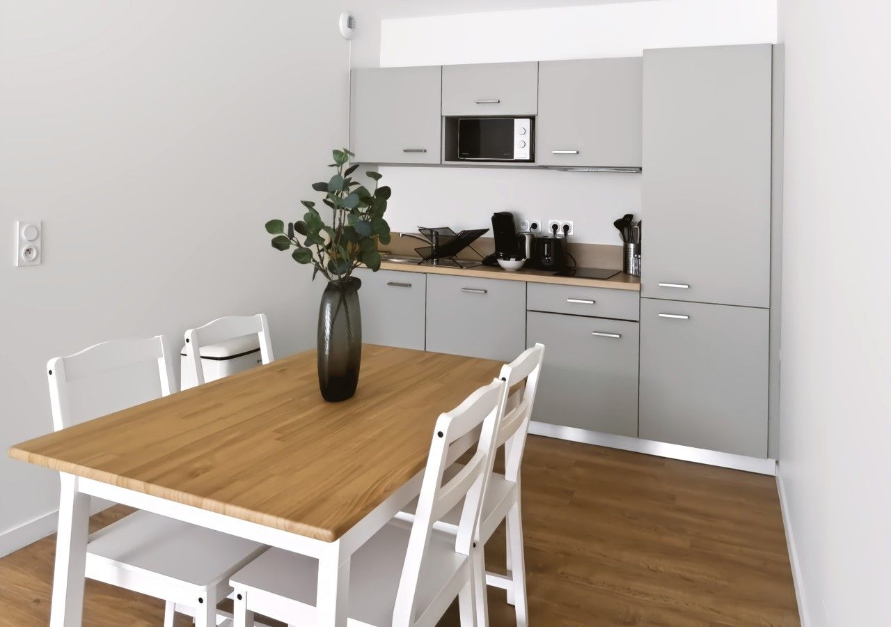 Een moderne keuken met witte kastjes, een magnetron en een koffiezetapparaat op het aanrecht.