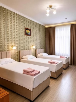 A hotel room with three beds, a wooden floor, a patterned wallpaper, and a picture on the wall. - HAYAT inn KHIVA (Khiva)