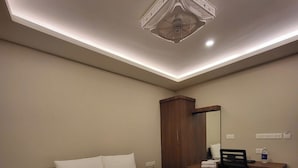 Hotellihuone, jossa on suuri sänky, työpöytä, tuoli, vaatekaappi ja kattovalaisin.