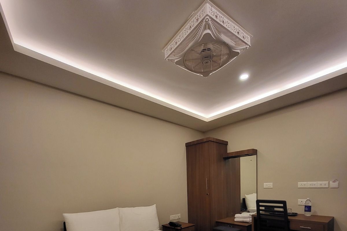 Habitación de hotel con una cama grande, un escritorio, una silla, un armario y una lámpara en el techo.