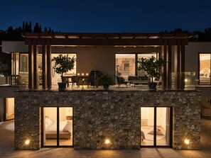 Un espacio exterior moderno con pared de piedra, comedor y una zona de estar acogedora.