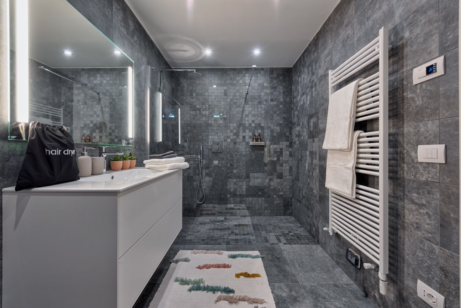 Une salle de bain moderne avec une douche à parois de verre, un meuble-lavabo blanc et un porte-serviettes.