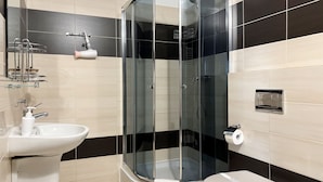 Um banheiro moderno com chuveiro envidraçado, pia branca e vaso sanitário.