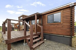 A wooden cabin with a deck, a staircase, and a metal door. - Peaceful Riverfront Cabin with Scenic Outdoor Deck in Ashton, Idaho (Ashton)