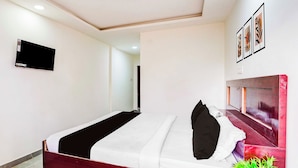 A hotel room with a bed, a television mounted on the wall, and a plant on the floor. - Townhouse Emerald Mall Lucknow (Lucknow)