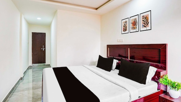 A hotel room with a bed, a nightstand with a plant, and a door leading to another room. - Townhouse Emerald Mall Lucknow (Lucknow)