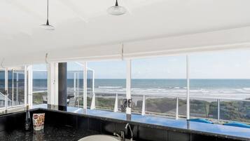 A bathroom with a large window, a sink, and a bottle of shampoo.