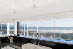 Ein Badezimmer mit einem großen Fenster, einem Waschbecken und einer Shampoo-Flasche.