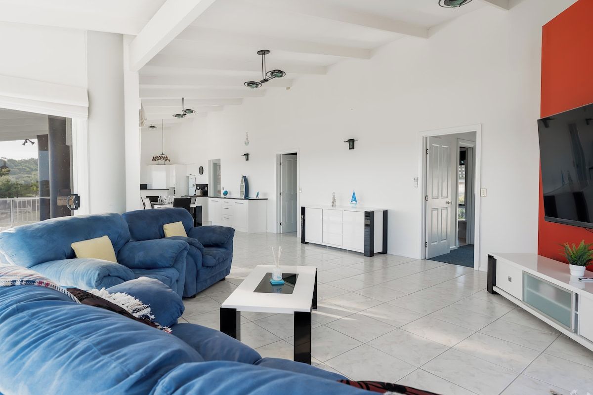 A modern living room with a blue sofa, a coffee table, and a kitchen area in the background.