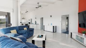 A modern living room with a blue sofa, a coffee table, and a kitchen area in the background.