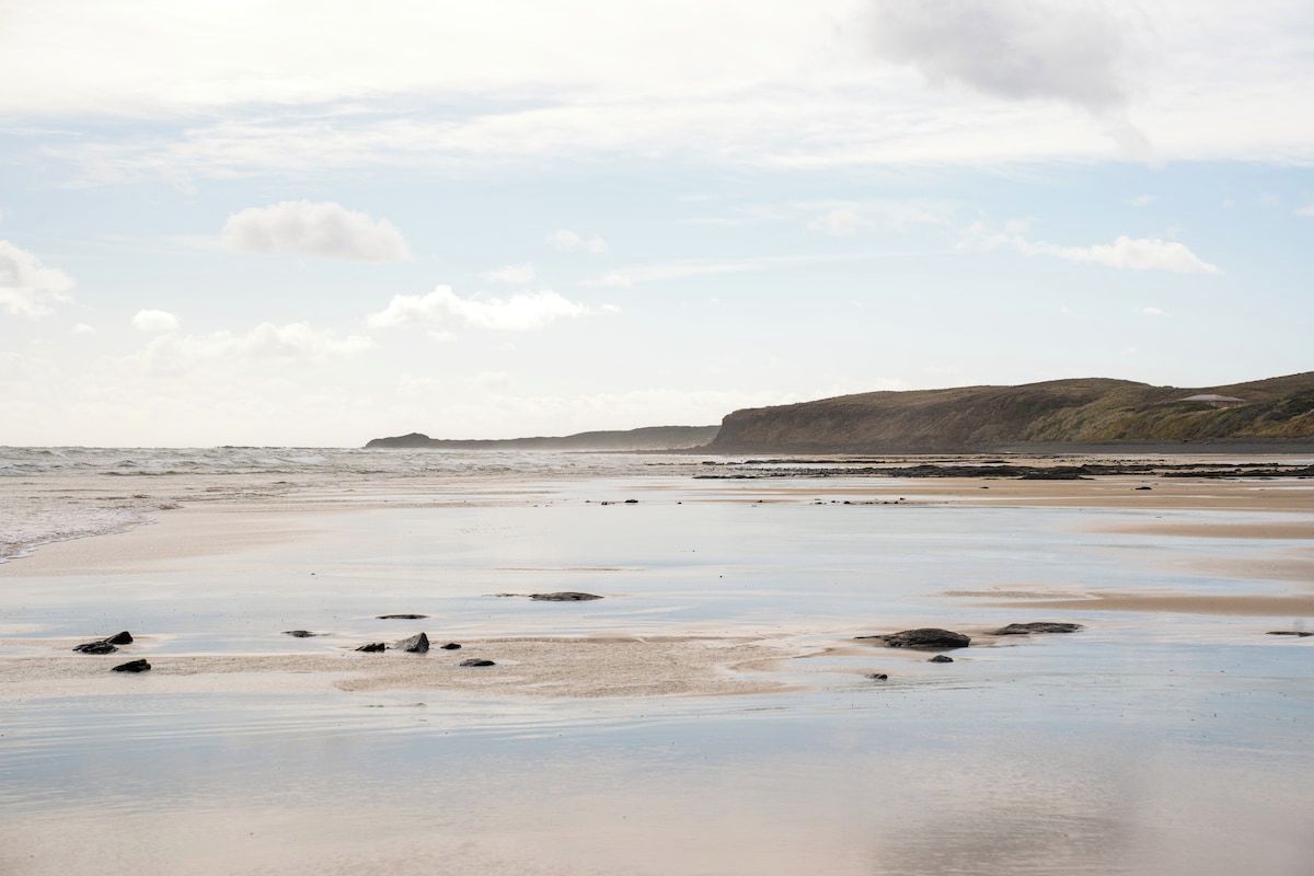 A beach with a sandy shore and scattered rocks.