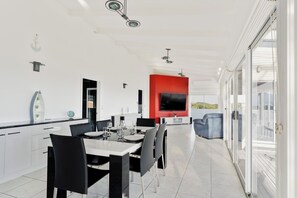 Una cuina moderna amb armaris blancs, una zona de menjador amb cadires negres i una paret vermella d'accentuació.