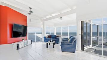 A modern living room with a large TV, a blue sofa, and a coffee table.