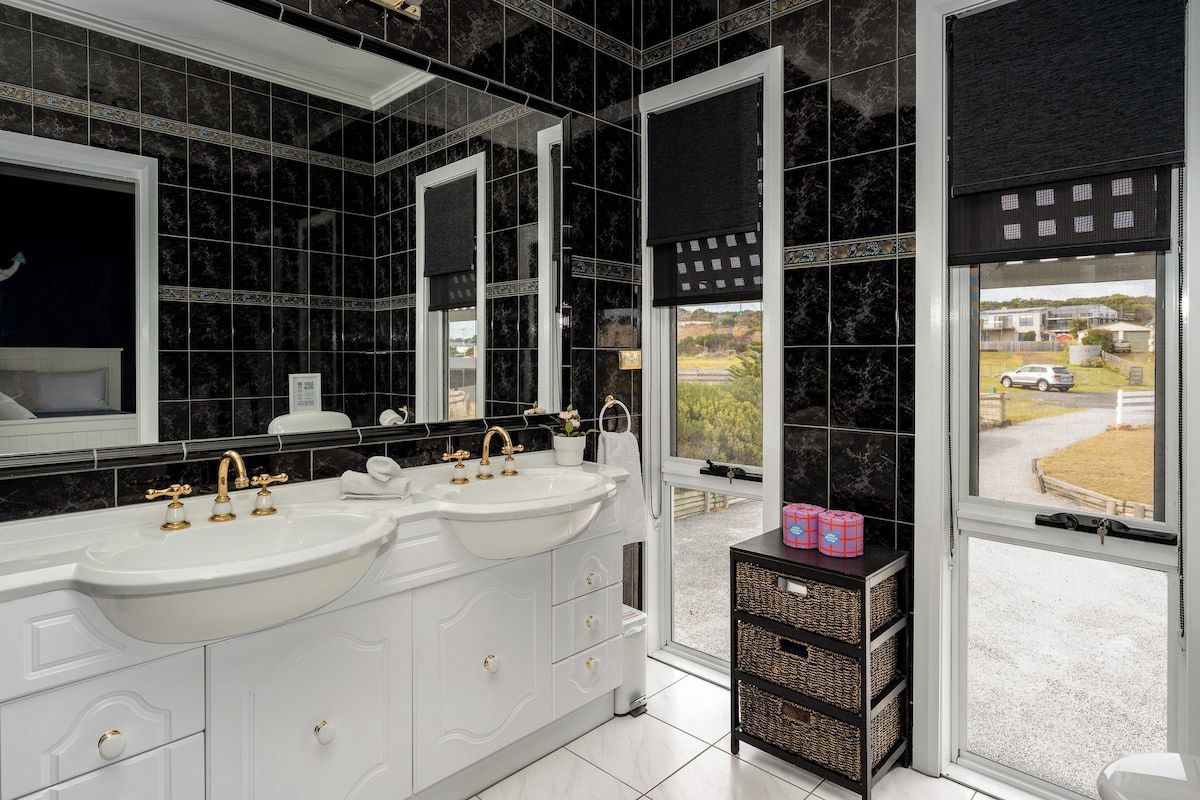 Un bagno con due lavandini, uno specchio grande e vista sull'esterno.