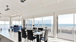 A spacious dining area with a view of the ocean, modern furniture, and large windows. - Shack Vibes, Direct Beach Access (Low Head)