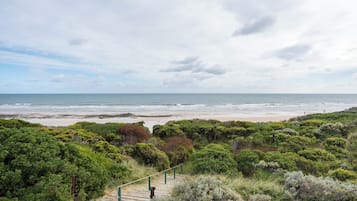 A coastal landscape with a beach, dense greenery, and a staircase leading down to the shore.