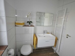 Un bany amb vàter, rentapel, mirall i penjador de tovalloles.