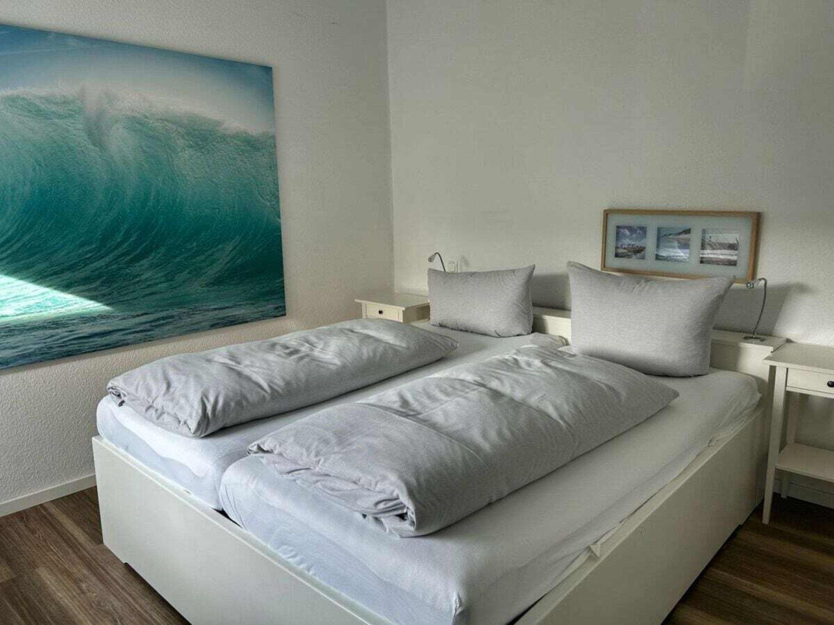 A bedroom with a bed, two bedside tables, and a large wall painting.
