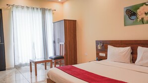Hotellihuone, jossa on sänky, työpöytä, tuoli, vaatekaappi ja taulu seinällä.