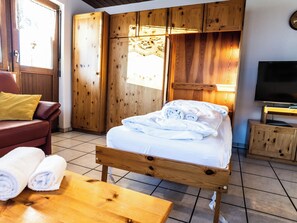 A hotel room with a wooden bed, a TV, a wooden wardrobe, and a red leather sofa. - Sportina 21 2. OG Süd-Ost Appartement/Fewo, Bad, WC by Interhome (Riederalp)