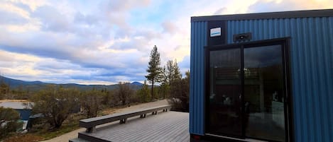 A modern building with a large glass door and a wooden deck.